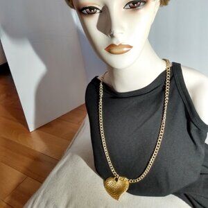 Gold tone heart shaped pendant necklace. Heart has moon, sun, & other symbols.